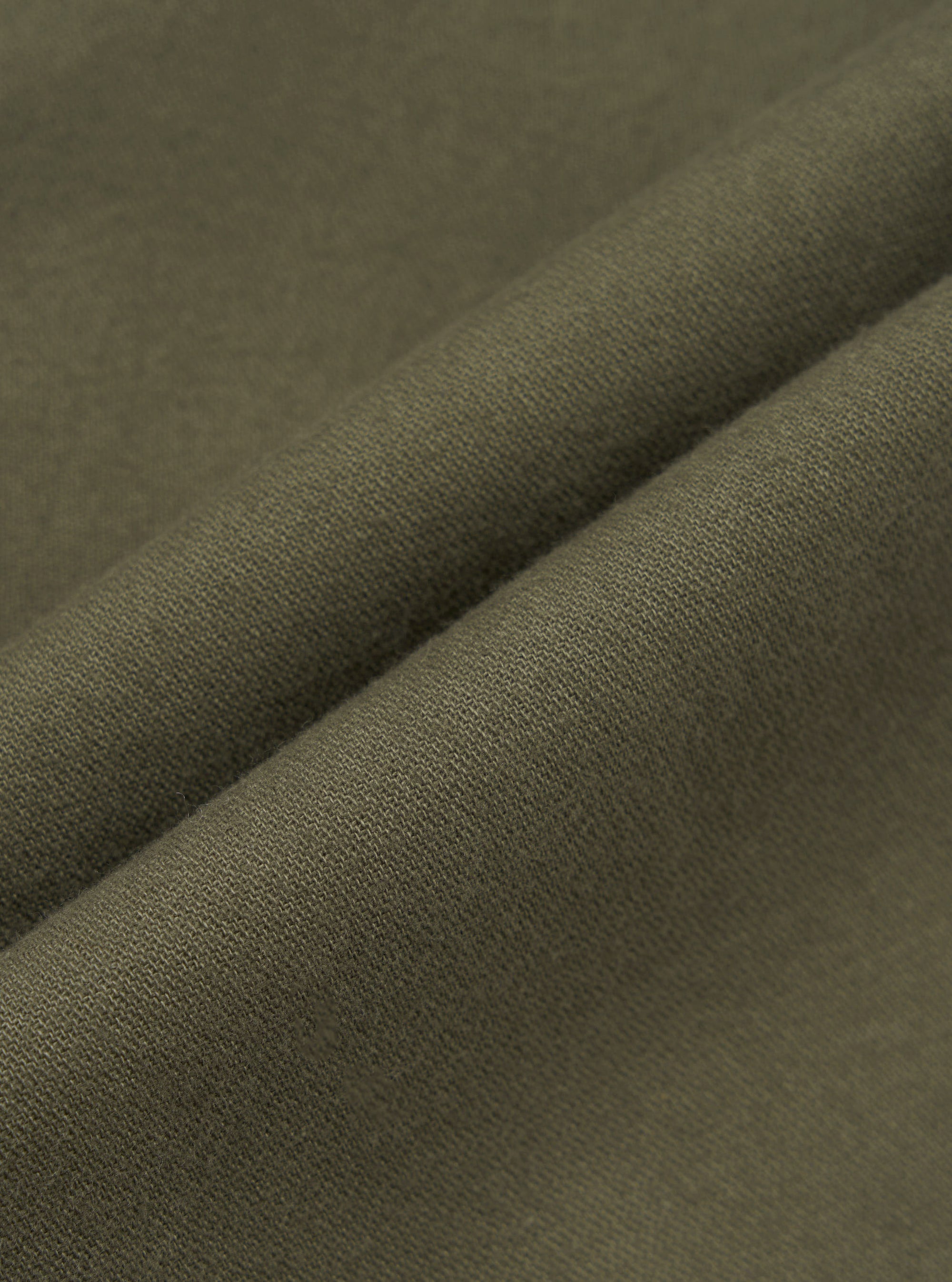 Close-up detail shot of olive brushed moleskin fabric, showing a folded edge that highlights the fine knit texture and soft surface finish. The solid, muted khaki-green cloth has a dense, smooth hand visible across the fold. No background is visible.