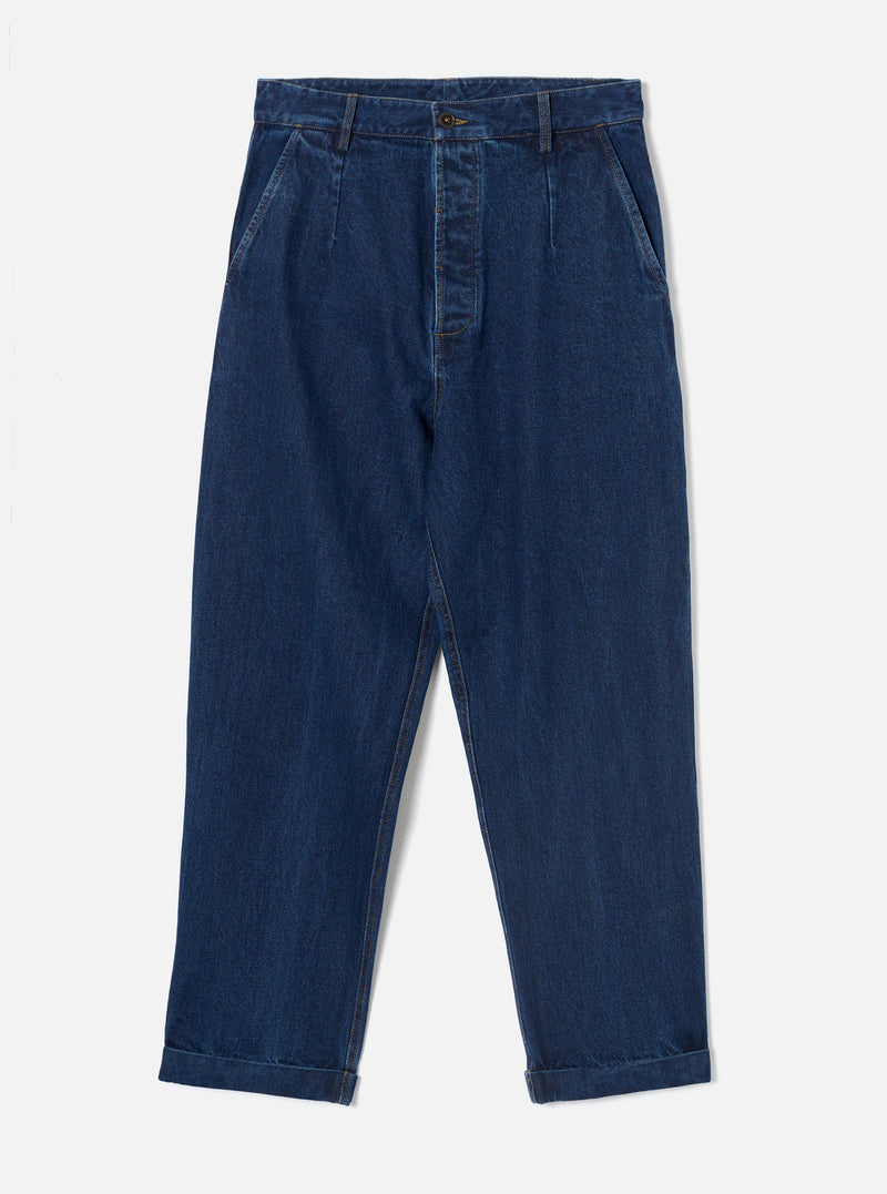 Indigo work denim super chino laid flat on a light grey studio backdrop. Dark indigo denim with a wide, tapered leg and single pleat at each hip. Structured waistband with a single button fastening, belt loops, and angled side pockets. Cuffed hems. Contrast topstitching throughout.