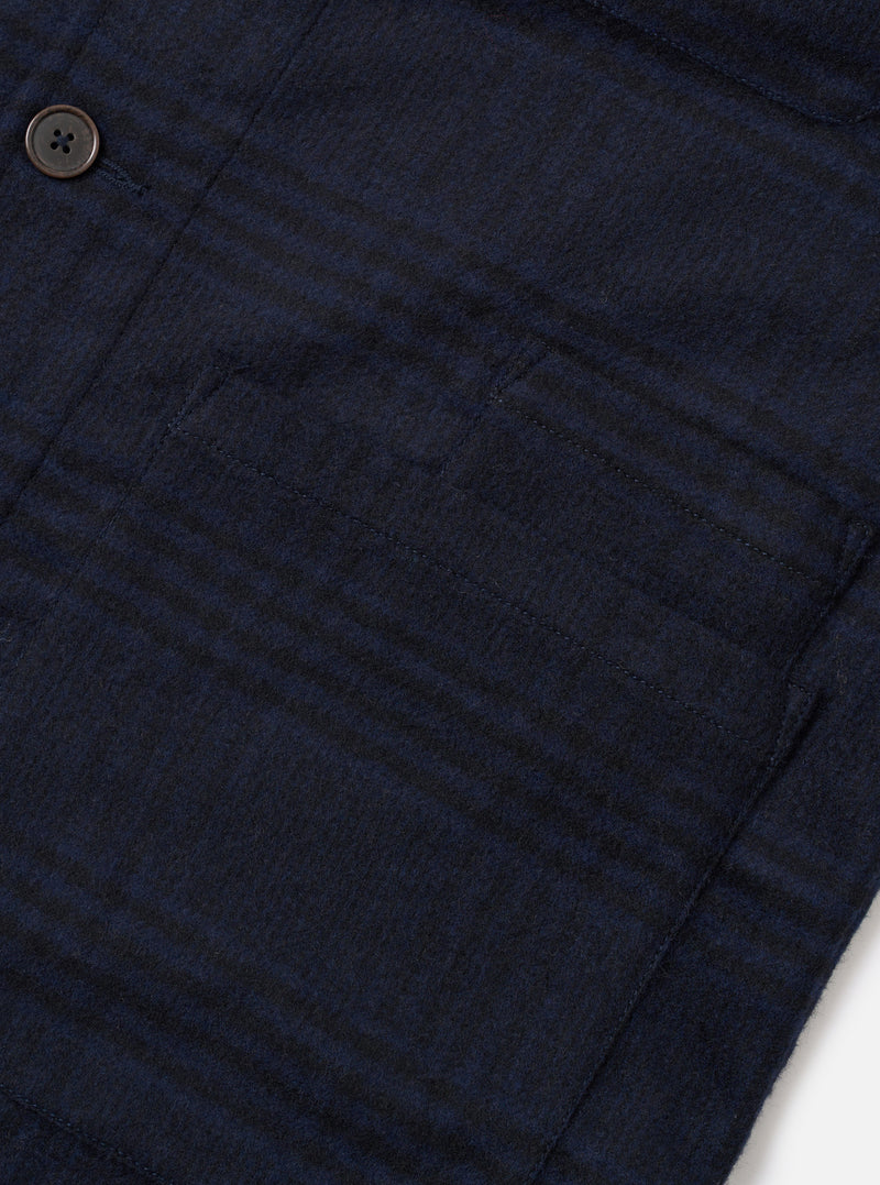 Close-up flat lay of the navy Bob Wool Mix Bakers Overshirt on a white surface, showing a large patch chest pocket with topstitched edges and a dark horn-effect button above. The fabric has a brushed wool-mix texture with a subtle dark navy check pattern.