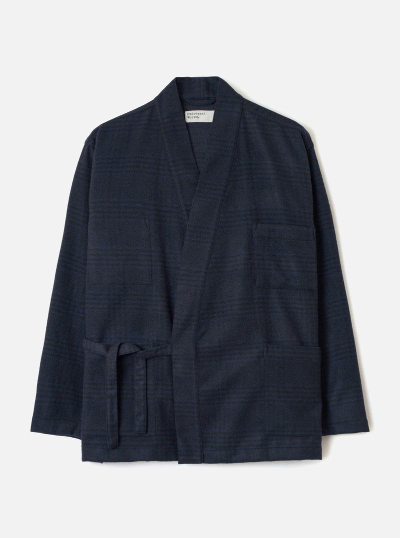 Navy wool mix Kyoto work jacket in a tonal glen plaid pattern, flat lay on a light grey backdrop. The open-front jacket features a shawl collar, two large patch pockets at the hip, a chest patch pocket, and a self-tie belt at the waist. Long sleeves with plain cuffs. Universal Works woven label at the neckline.