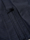 Close-up detail of the navy wool mix Kyoto Work Jacket showing a welt pocket with a fabric tab fastening. The tonal navy and dark green check pattern is visible across the brushed wool mix fabric. Shot flat, no model or mannequin present.