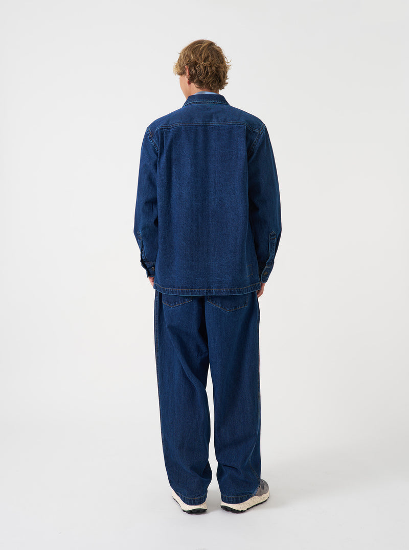 A rear view of a model wearing the Indigo Contrast Stitch Work Denim Fatigue Shirt. The image highlights the dark blue denim construction, contrast seam details, and relaxed fit set against a plain neutral background.