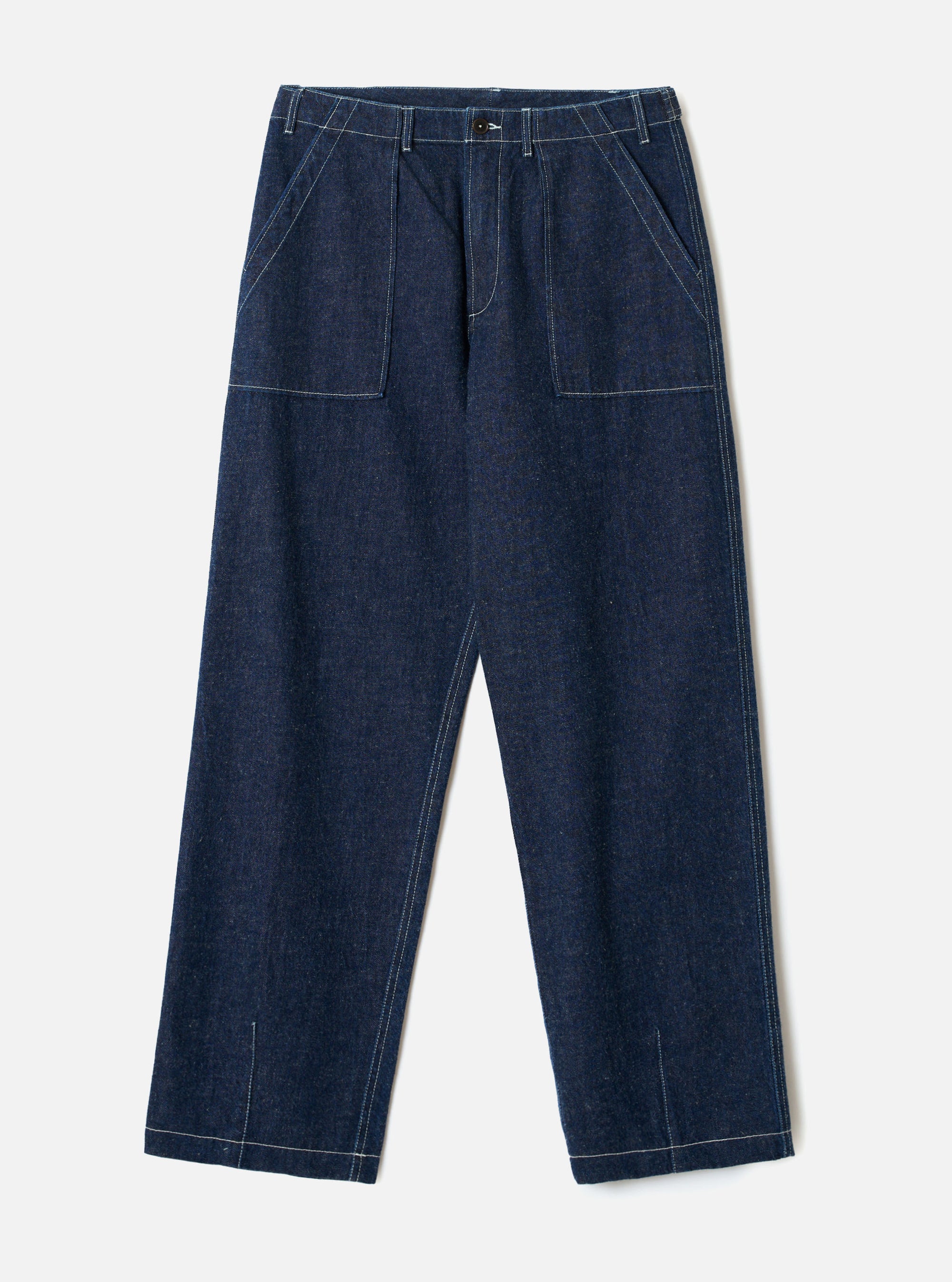Indigo denim fatigue trousers laid flat on a light grey seamless backdrop. Wide-leg cut in raw indigo denim with visible white contrast topstitching throughout. Structured waistband with a single button fastening and no belt loops. Two large square patch pockets sit on the front thighs. Angled side seams and vent slits at the hem.
