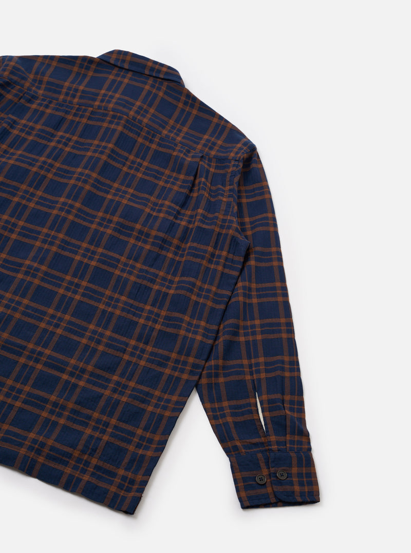 A studio shot displaying the rear view of the Navy/Brown Young Check CPO Shirt on a white background. The image highlights the clean back yoke, straight hemline, and navy and brown woven check pattern.