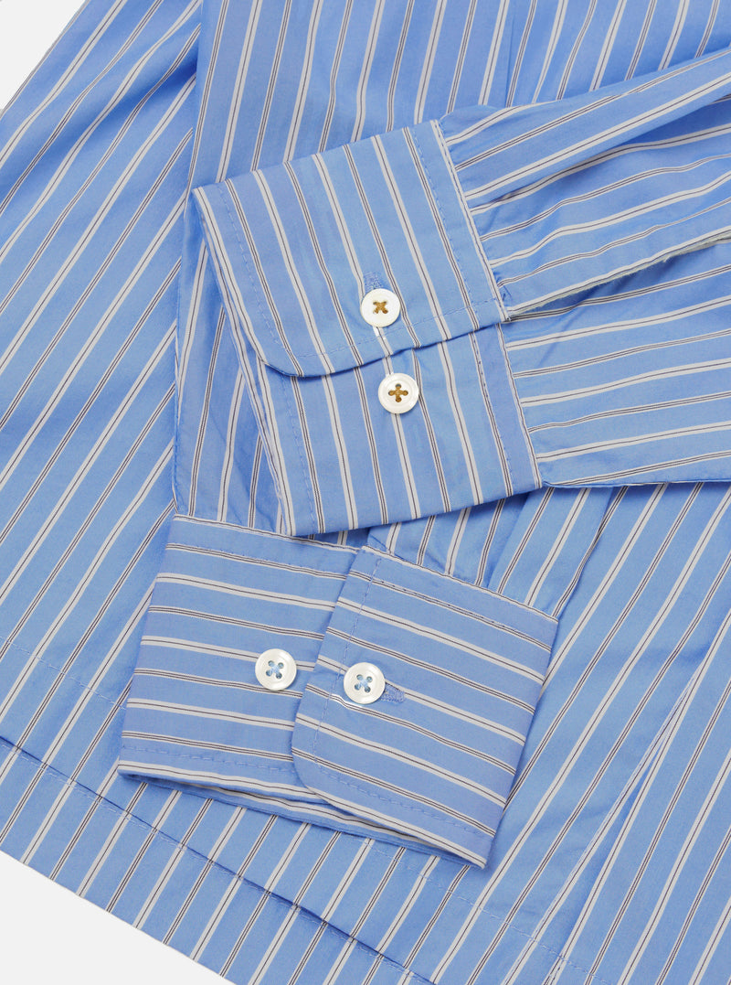 Close-up flat lay of the blue stripe Refab compact cotton Lucky shirt, focusing on both cuffs. The smooth cotton fabric features narrow dark and white stripes on a blue ground. Each double-button barrel cuff shows two white mother-of-pearl buttons. Shot on a white studio backdrop.