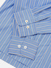 Close-up flat lay of the blue stripe Refab compact cotton Lucky shirt, focusing on both cuffs. The smooth cotton fabric features narrow dark and white stripes on a blue ground. Each double-button barrel cuff shows two white mother-of-pearl buttons. Shot on a white studio backdrop.