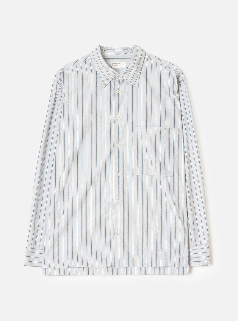 Flat lay of a grey striped long-sleeve shirt on a light grey seamless backdrop. The shirt features a rounded point collar, a concealed placket with cream buttons, a left chest patch pocket, and buttoned barrel cuffs. The fabric is a compact cotton with vertical blue and dark navy pinstripes on a grey ground. A Universal Works woven label is visible at the collar.