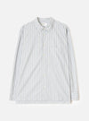 Flat lay of a grey striped long-sleeve shirt on a light grey seamless backdrop. The shirt features a rounded point collar, a concealed placket with cream buttons, a left chest patch pocket, and buttoned barrel cuffs. The fabric is a compact cotton with vertical blue and dark navy pinstripes on a grey ground. A Universal Works woven label is visible at the collar.