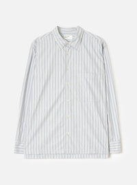 Flat lay of a grey striped long-sleeve shirt on a light grey seamless backdrop. The shirt features a rounded point collar, a concealed placket with cream buttons, a left chest patch pocket, and buttoned barrel cuffs. The fabric is a compact cotton with vertical blue and dark navy pinstripes on a grey ground. A Universal Works woven label is visible at the collar.