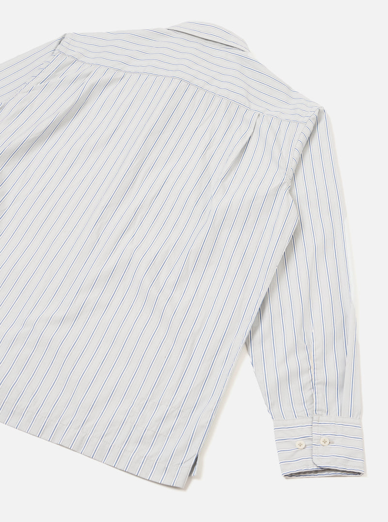 Flat lay of the grey stripe compact cotton Lucky Shirt, showing the back panel and one long sleeve. Blue pinstripes run vertically on a white-grey ground. A back yoke seam is visible at the shoulder. The cuff features two white buttons and sits fully extended. Light grey seamless studio backdrop.