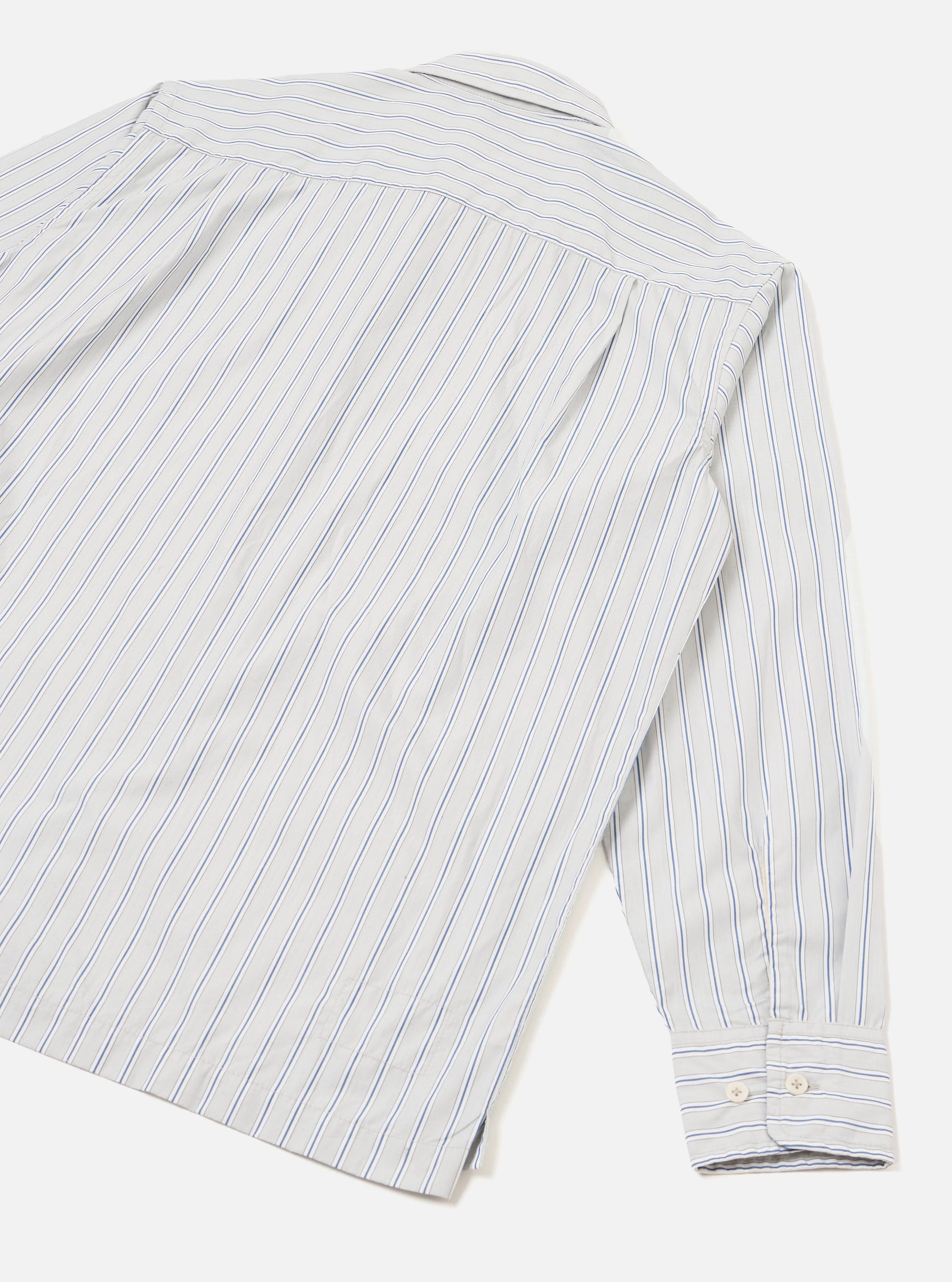 Flat lay of the grey stripe compact cotton Lucky Shirt, showing the back panel and one long sleeve. Blue pinstripes run vertically on a white-grey ground. A back yoke seam is visible at the shoulder. The cuff features two white buttons and sits fully extended. Light grey seamless studio backdrop.
