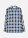 Blue check ombre plaid long-sleeve shirt laid flat on a light grey studio backdrop. Features a point collar, full-length button placket with white buttons, two flap chest pockets, and buttoned cuffs. The check pattern blends blue, navy and olive tones with a soft, diffused ombre effect.