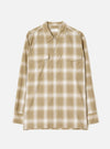 Sand and cream ombre check long-sleeve shirt laid flat on a light grey studio backdrop. Features a pointed collar, full-length button placket with cream buttons, two flap chest pockets, and buttoned cuffs. Universal Works woven label visible at the neckline.