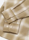 Flat lay close-up of the sand check shirt's cuffs and sleeves on a white surface. The fabric features a tonal ombre check pattern in beige, sand and cream. Both buttoned barrel cuffs are visible, each fastened with two cream four-hole buttons. The lightweight woven fabric has a subtle sheen.