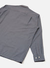 Flat lay of a blue and brown mini gingham check shirt on a white studio surface. The upper back, collar and one full sleeve are visible. The spread collar lies flat and the buttoned cuff features two small silver buttons. The woven check fabric has a fine texture throughout.