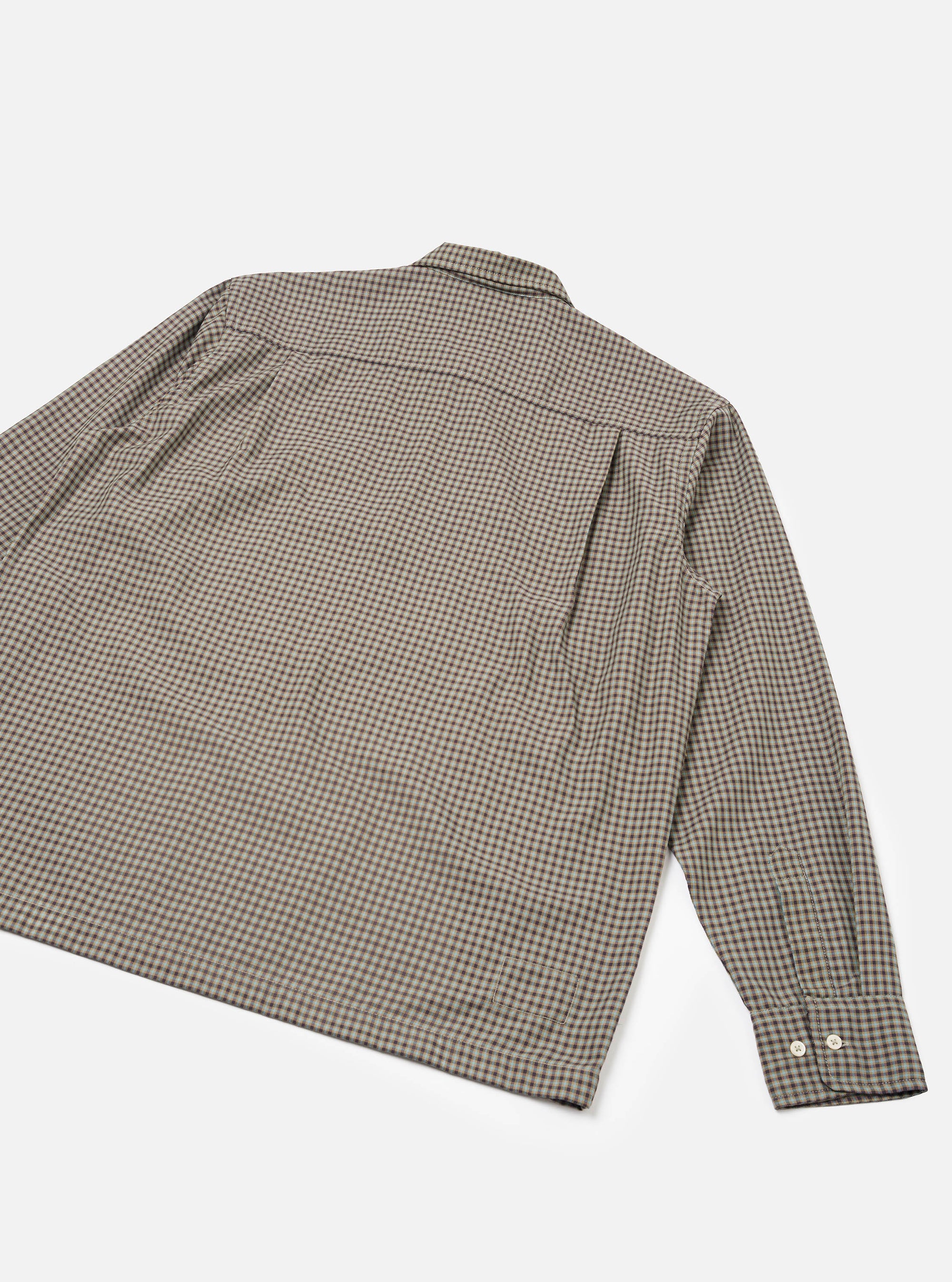 Flat lay of a sand and olive small gingham check shirt, shot from the back at an angle on a white studio surface. The spread collar, back yoke seam, and single long sleeve are visible. The cuff features two small cream buttons. Woven cotton fabric in a fine two-tone check.