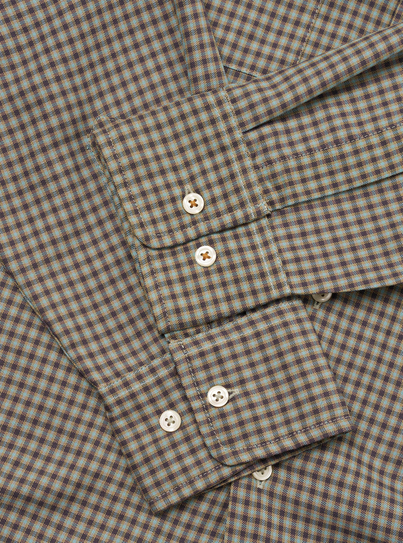 Close-up flat lay of the Sand/Olive Parker Check Attendant Shirt, showing the button placket with four pearlescent buttons and a chest patch pocket with a pointed flap. The fabric features a fine micro-check pattern in sand, olive, and dark brown. No model or mannequin present.