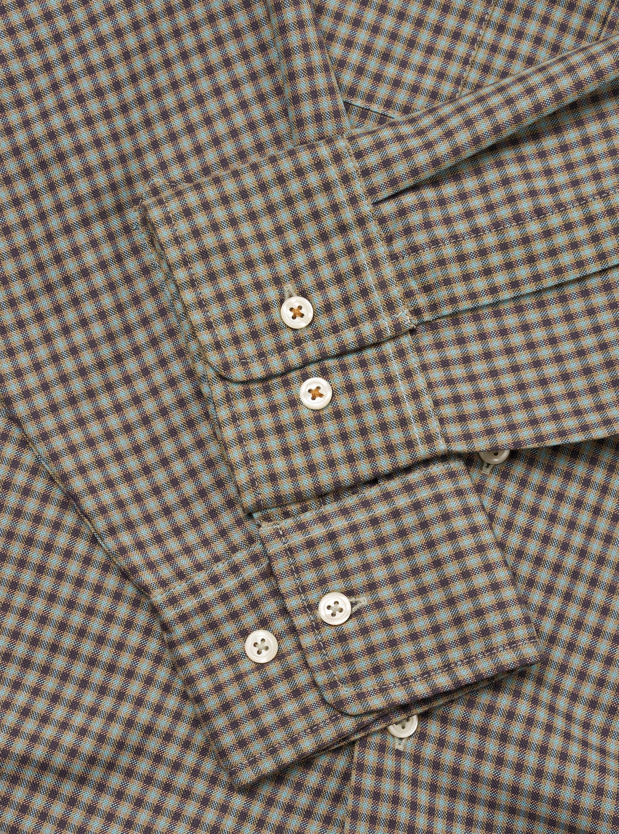 Close-up flat lay of the Sand/Olive Parker Check Attendant Shirt, showing the button placket with four pearlescent buttons and a chest patch pocket with a pointed flap. The fabric features a fine micro-check pattern in sand, olive, and dark brown. No model or mannequin present.