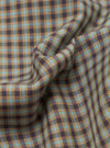 Close-up of the sand and olive Parker Check fabric, showing a small-scale gingham check woven in tan, dark brown, and pale blue yarns. The textured weave has a coarse, basketweave-like quality. The cloth is gathered into soft folds at the centre, revealing the pattern's depth and colour variation across the surface.