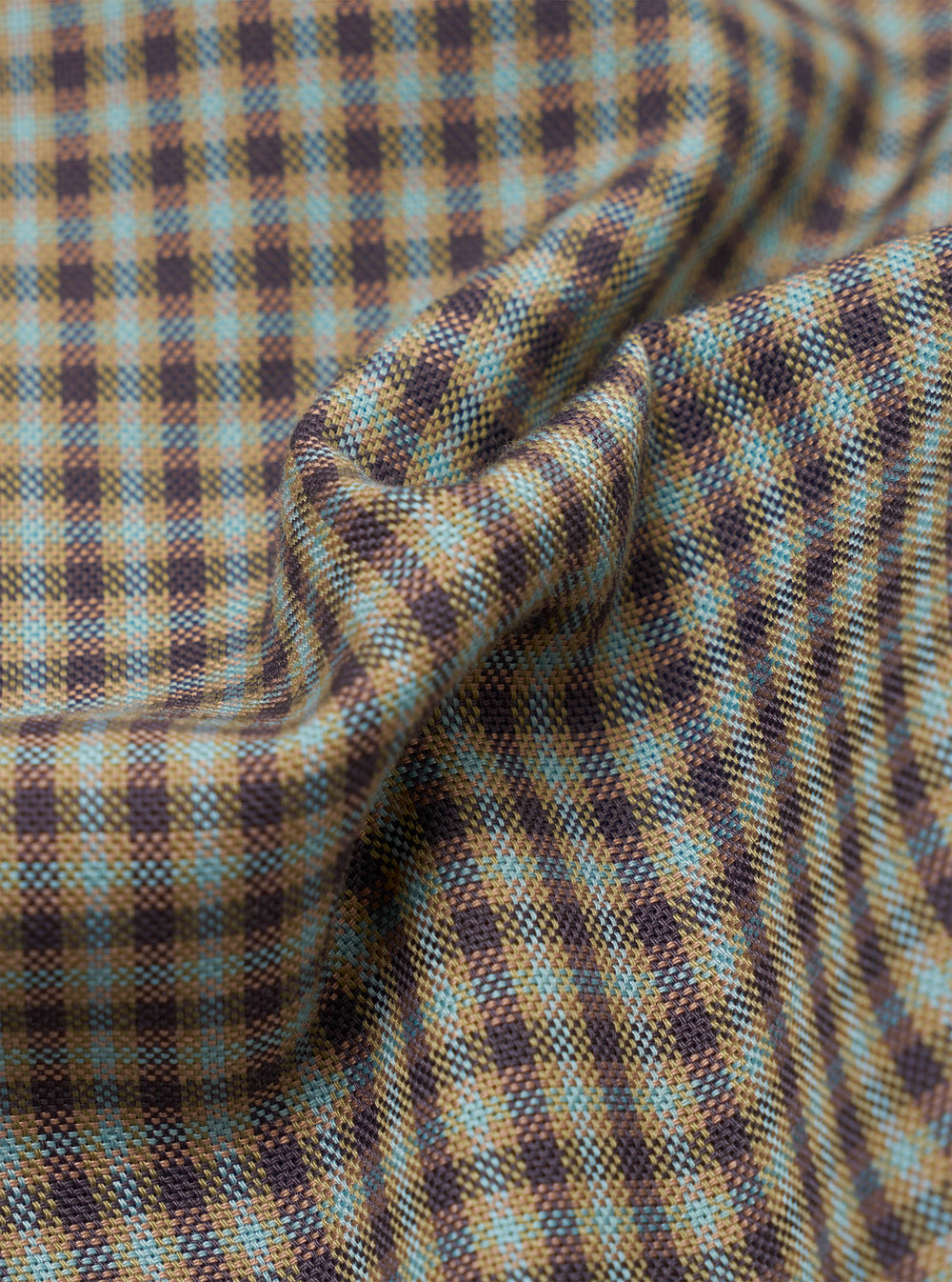 Close-up of the sand and olive Parker Check fabric, showing a small-scale gingham check woven in tan, dark brown, and pale blue yarns. The textured weave has a coarse, basketweave-like quality. The cloth is gathered into soft folds at the centre, revealing the pattern's depth and colour variation across the surface.