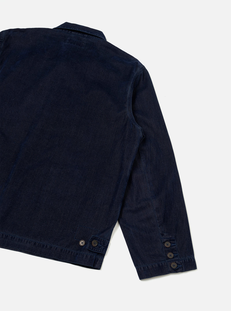 A back studio view of the Navy Flock Chambray Warmus Jacket against a plain neutral background. The dark blue cotton chore-style jacket displays a clean back panel, neat shoulder seams, and a straight hemline silhouette.