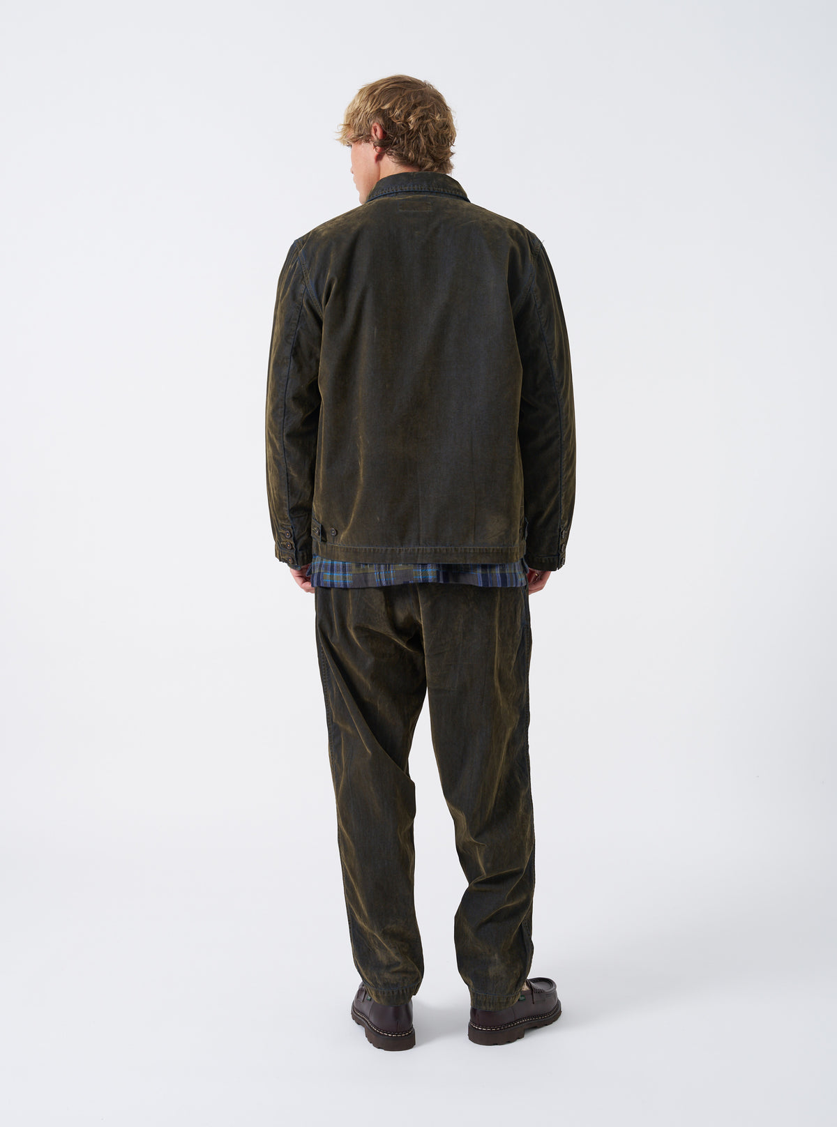 A back view of a model wearing the Olive Flock Chambray Warmus Jacket set against a plain backdrop. The shot showcases the smooth olive green cotton fabric across the back, clean shoulders, and relaxed fit.