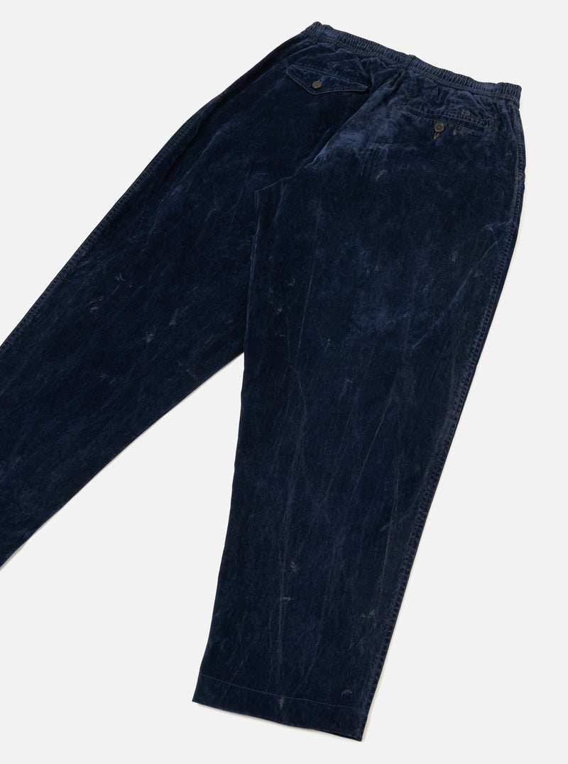 A back studio view of the Navy Flock Chambray Pleated Track Pant against a plain background. The dark blue trousers feature rear patch pockets, a straight waistline seam, and a loose tapered silhouette.