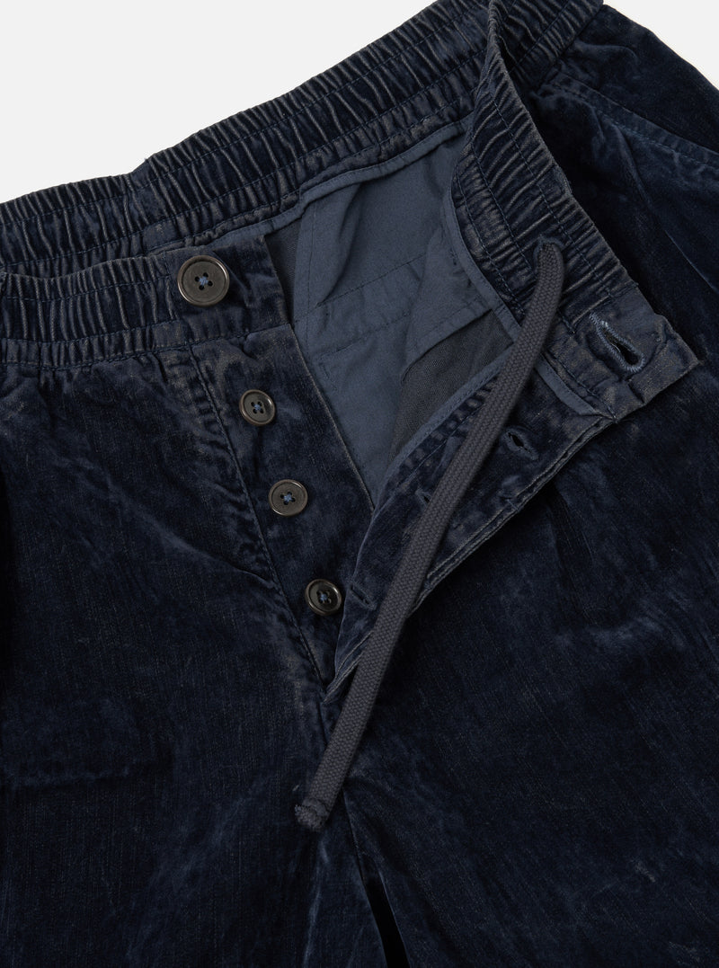 A close-up detail shot of the Navy Flock Chambray Pleated Track Pant set against a plain backdrop, showcasing the navy blue flock chambray cotton fabric texture, front pleats, and drawstring waistband construction.