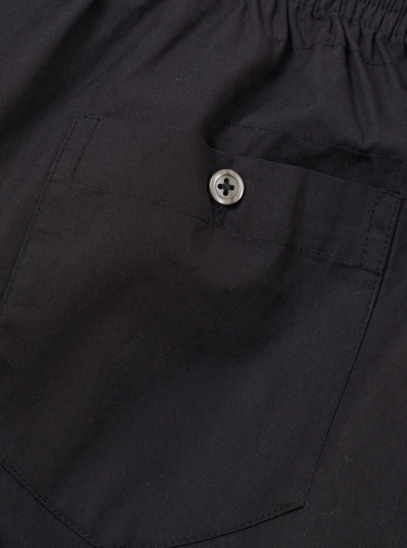 Rear view of the Universal Works Black Broadcloth Boxer Shorts laid flat against a plain backdrop. Showcases the clean back seams, elastic waistband, and smooth texture of the black cotton broadcloth fabric.