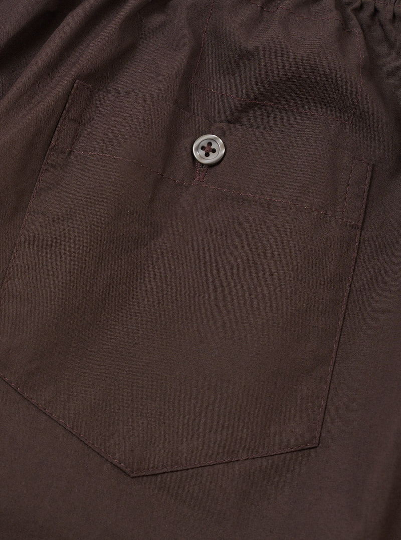 Back view of the Universal Works Brown Broadcloth Boxer Shorts against a neutral studio background. Highlights the clean rear paneling, comfortable elastic waistband, and warm brown cotton material.