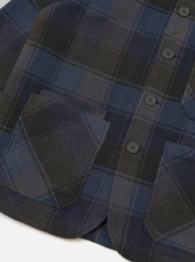 A detailed close-up shot of the Universal Works Navy/Brown Berlin Wool Check OG Bakers Chore Jacket on a plain background, highlighting the signature angled top buttonhole and classic collar details.