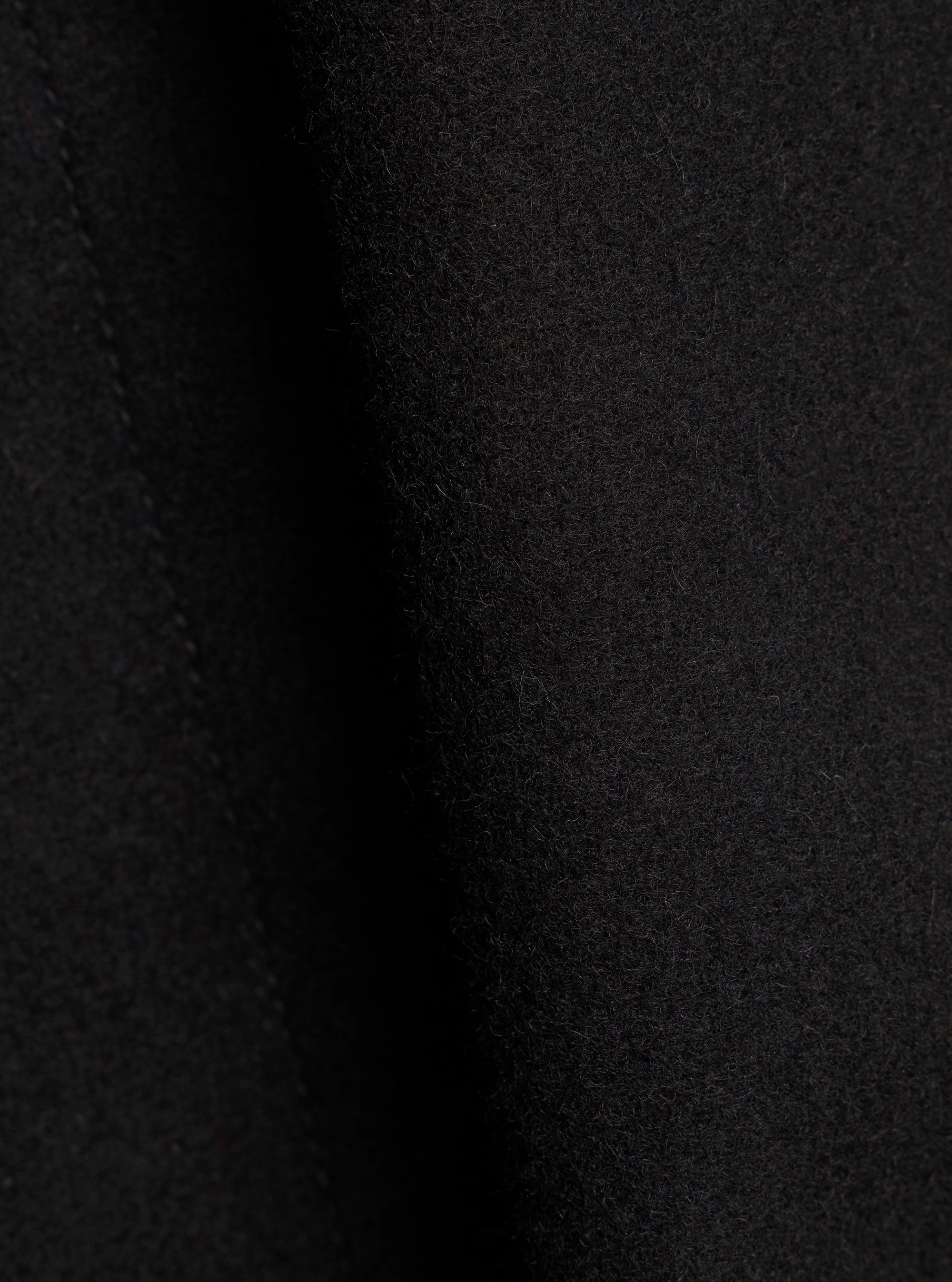 Close-up of the black Mowbray Boston Parka fabric, showing a soft, brushed wool-blend texture with fine surface fibres. The material has a dense, slightly napped finish in a deep black tone. No garment details or construction features are visible in this tight fabric shot.