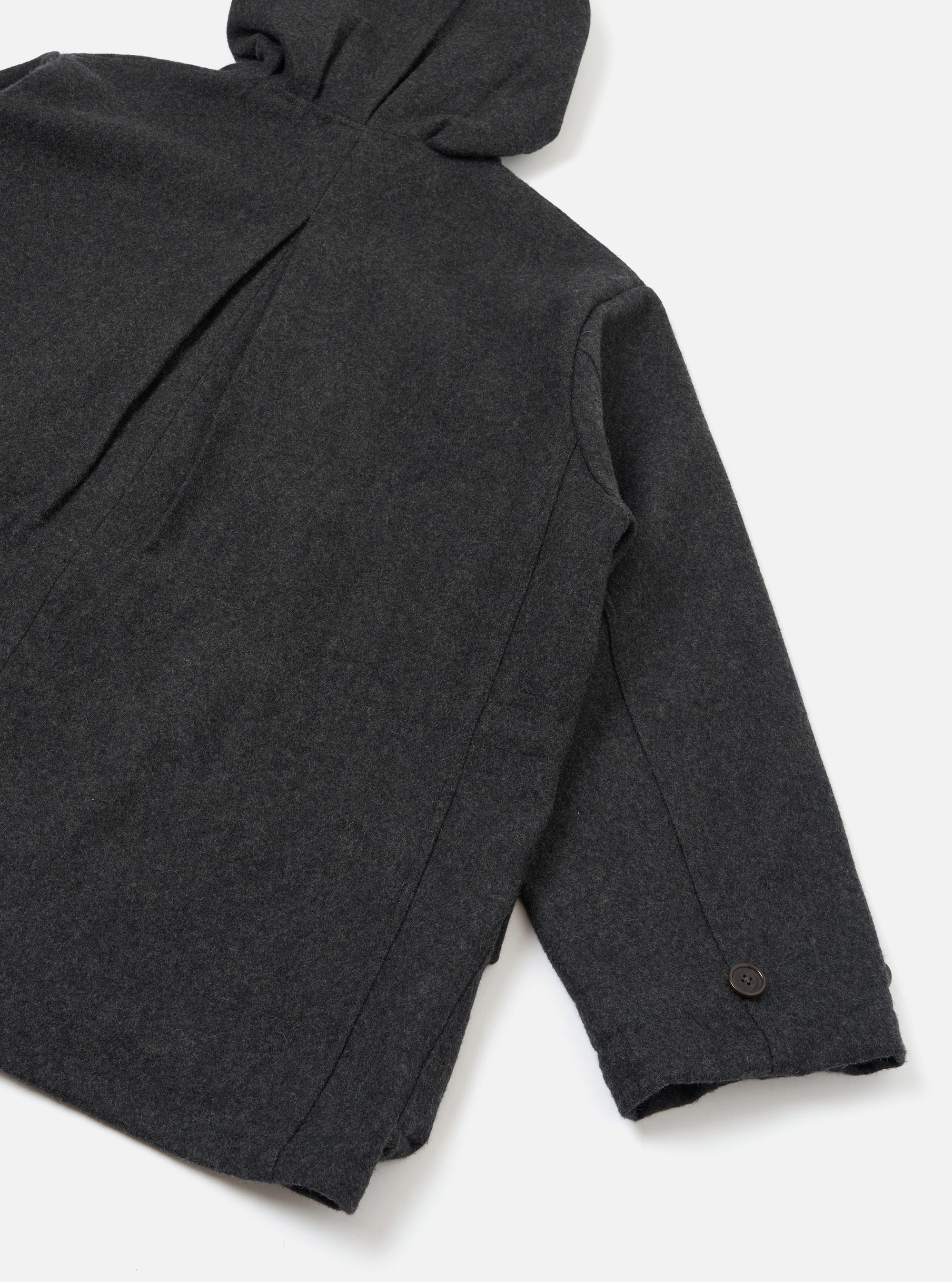 Close-up flat lay of the grey marl Mowbray Boston Parka on a white studio surface, showing the back panel and one sleeve. A hood with a drawcord is visible at the top. The cuff features a single dark button. Panelled seam detail runs along the sleeve. The wool-blend fabric has a fine marl texture throughout.