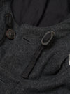 Close-up of the grey marl wool-texture parka's hood and collar area. A dark brown four-hole button fastens the hood toggle loop on the left. A braided drawcord threads through a metal eyelet on the right. The hood's dark navy lining is visible behind the collar. Shot on a plain light grey seamless backdrop.