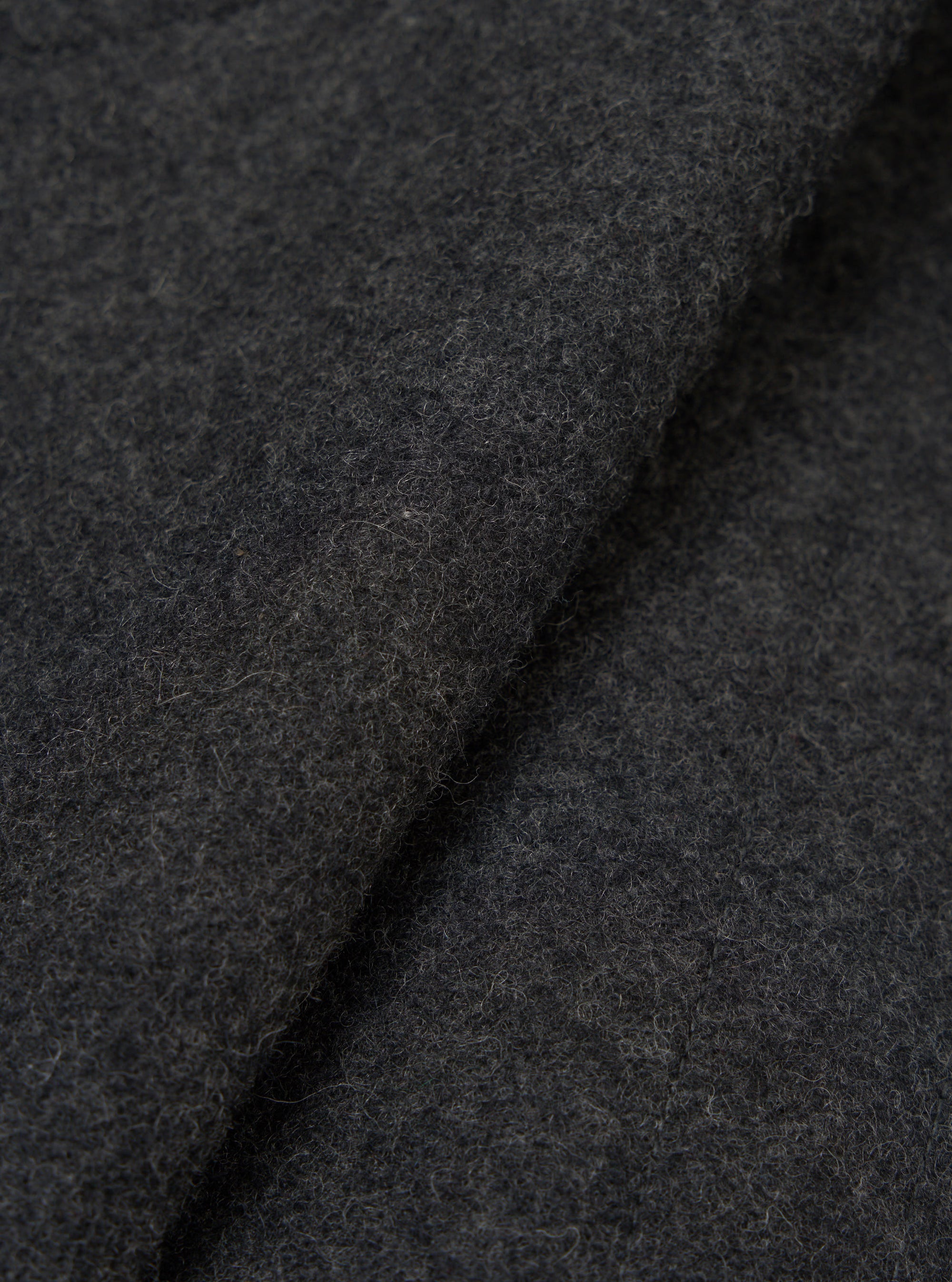 Close-up fabric detail of the grey marl Mowbray Boston Parka. The shot shows the charcoal marl wool-effect fabric folded and rolled, revealing its dense, lightly brushed texture with fine flecks throughout. No garment details or construction features are visible.