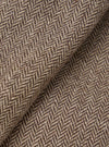 Close-up detail shot of a brown wool herringbone jacket fabric. The weave shows a classic chevron pattern in dark brown and oatmeal, with a lightly textured, slightly hairy wool surface. The fabric is folded to reveal depth and drape. No background is visible.