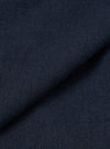 Close-up of navy wool herringbone fabric from the Ives Jacket, folded to show texture and weight. The tight herringbone weave shows dark navy and charcoal tones throughout. No background visible, the shot fills the frame with fabric detail only.