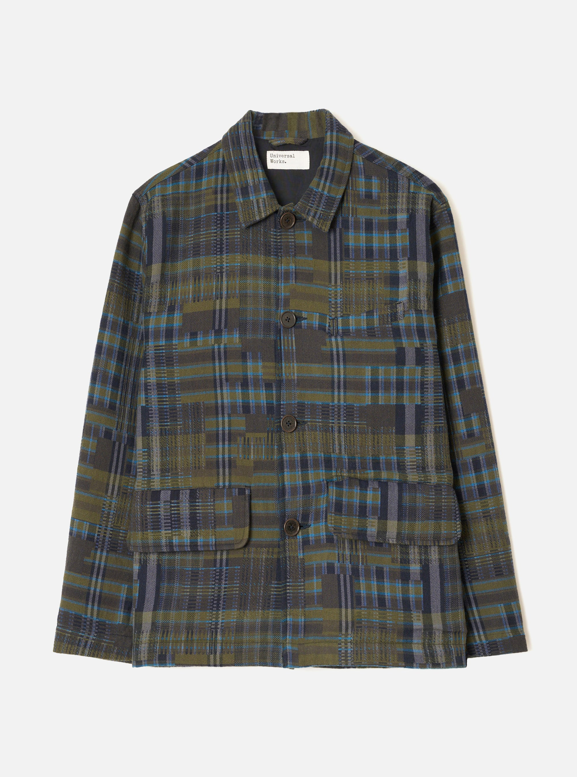 Olive shadows check chore jacket in a woven plaid of olive, navy and blue tones with a distressed check texture. Point collar, four-button placket with dark brown buttons, chest patch pocket and two large flap patch pockets at the hem. Universal Works woven label at the neck. Flat lay on a light grey studio backdrop.