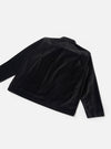 Black velvet zip overshirt laid flat on a light grey seamless backdrop, shot from a rear three-quarter angle. The soft, lustrous velvet fabric catches light across the back panel and long sleeves. A yoke seam runs across the upper back. A small woven label is visible at the lower left hem.