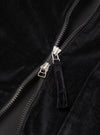 Close-up detail of the black velvet zip-front shirt, showing a two-way silver-toned zip with black plastic teeth, a black zip tape, and a fabric pull tab in matching black velvet. The soft, dense pile of the velvet fabric is visible on either side of the open zip.