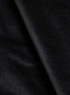 Close-up detail shot of black velvet fabric, showing a soft, dense pile texture with a diagonal fold running from top to bottom. The surface catches light subtly, highlighting the plush nap of the velvet. No garment construction details are visible.