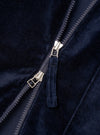 Close-up detail of the navy velvet zip-front shirt. A two-way silver-tone zip runs diagonally across the frame, partially open, with a fabric-covered navy velvet zip garage visible. The dense, soft velvet pile and a smooth navy lining are visible either side of the zip teeth. Plain white studio backdrop.