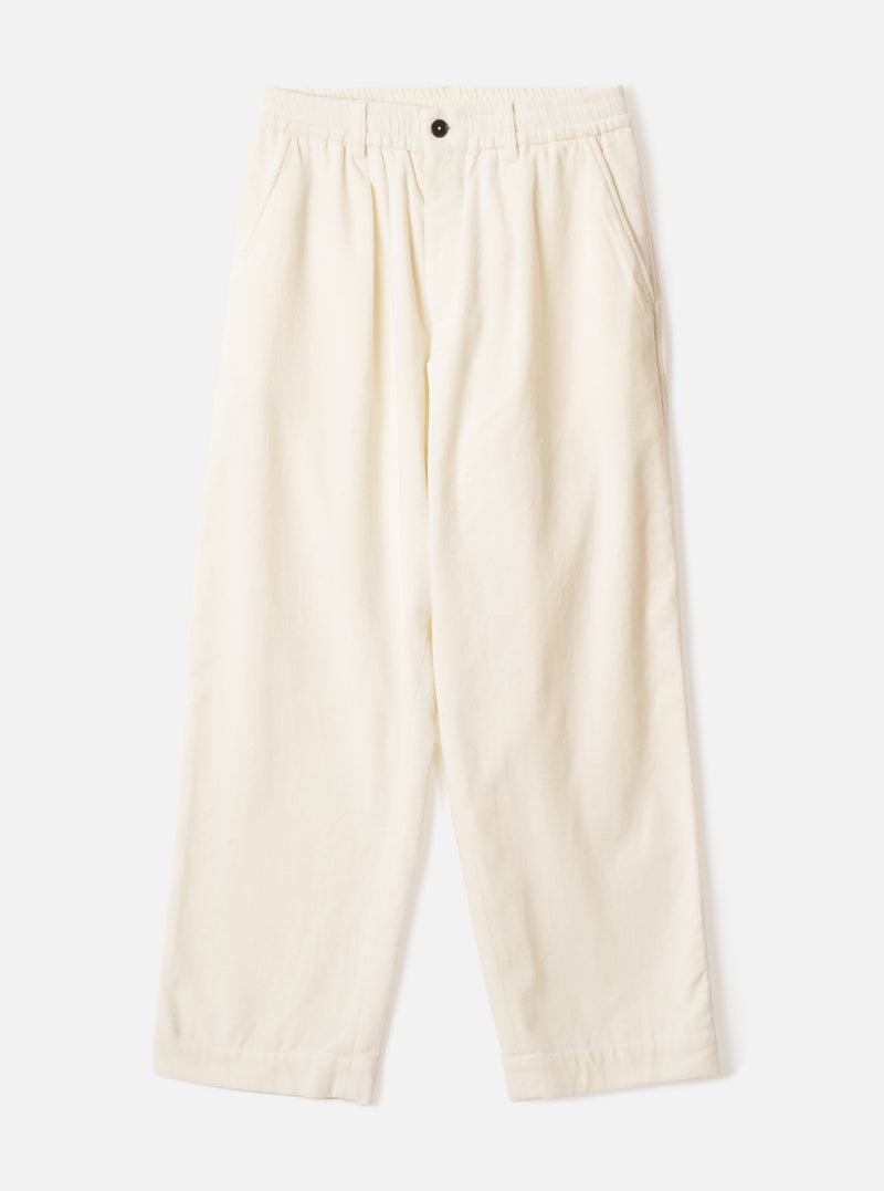 Ecru wide-leg velvet oxford trousers laid flat on a light grey background. The elasticated waistband features a single dark button at the centre front. Slash pockets sit at the hips. The fabric has a soft, fine-ribbed velvet texture. The silhouette is relaxed through the leg with a full-length hem.