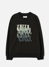 Black raglan sweatshirt laid flat on a light grey studio surface. Ribbed crew neck with a Universal Works woven label at the back neck. Ribbed cuffs and hem. Chest features a repeated "UW." graphic in blackletter style, fading from pale sage to dark charcoal across four stacked rows.