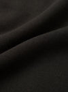 Close-up of black brushback fleece fabric, showing a soft, dense knit texture with a lightly napped surface. The fabric is folded and draped, revealing its weight and structure. No garment details or background are visible in this fabric detail shot.