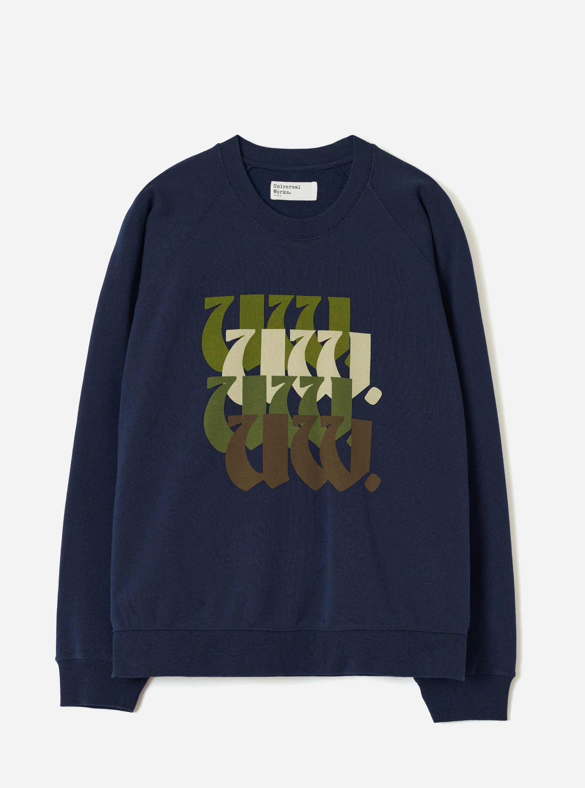 Navy brushback raglan sweatshirt laid flat on a light grey studio backdrop. Ribbed crew neck, ribbed cuffs and hem. A Universal Works label sits inside the collar. The chest features a stacked repeat "UW." graphic in blackletter script, graduating in colour from olive green through cream and dark green to brown.