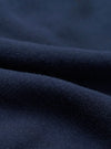 Close-up detail shot of navy brushback fleece fabric, showing a soft, dense looped texture on the reverse side and a smooth face. The material is folded to reveal both surfaces, highlighting the fabric's weight and finish.