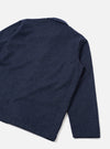 Flat lay of a navy check wool mix bakers overshirt on a light grey seamless backdrop. The shot shows the back and one sleeve at an angle. A small notched collar is visible at the top. The fabric features a fine white grid check on a navy ground with a slightly textured weave. The sleeve cuff is plain and unfinished in appearance.
