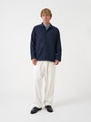 A front view of a model wearing the Universal Works Navy Check Bobby Wool Mix Bakers Overshirt. The dark blue check overshirt features a button front fastening, classic collar, chest pocket, and lower patch pockets against a plain neutral background.