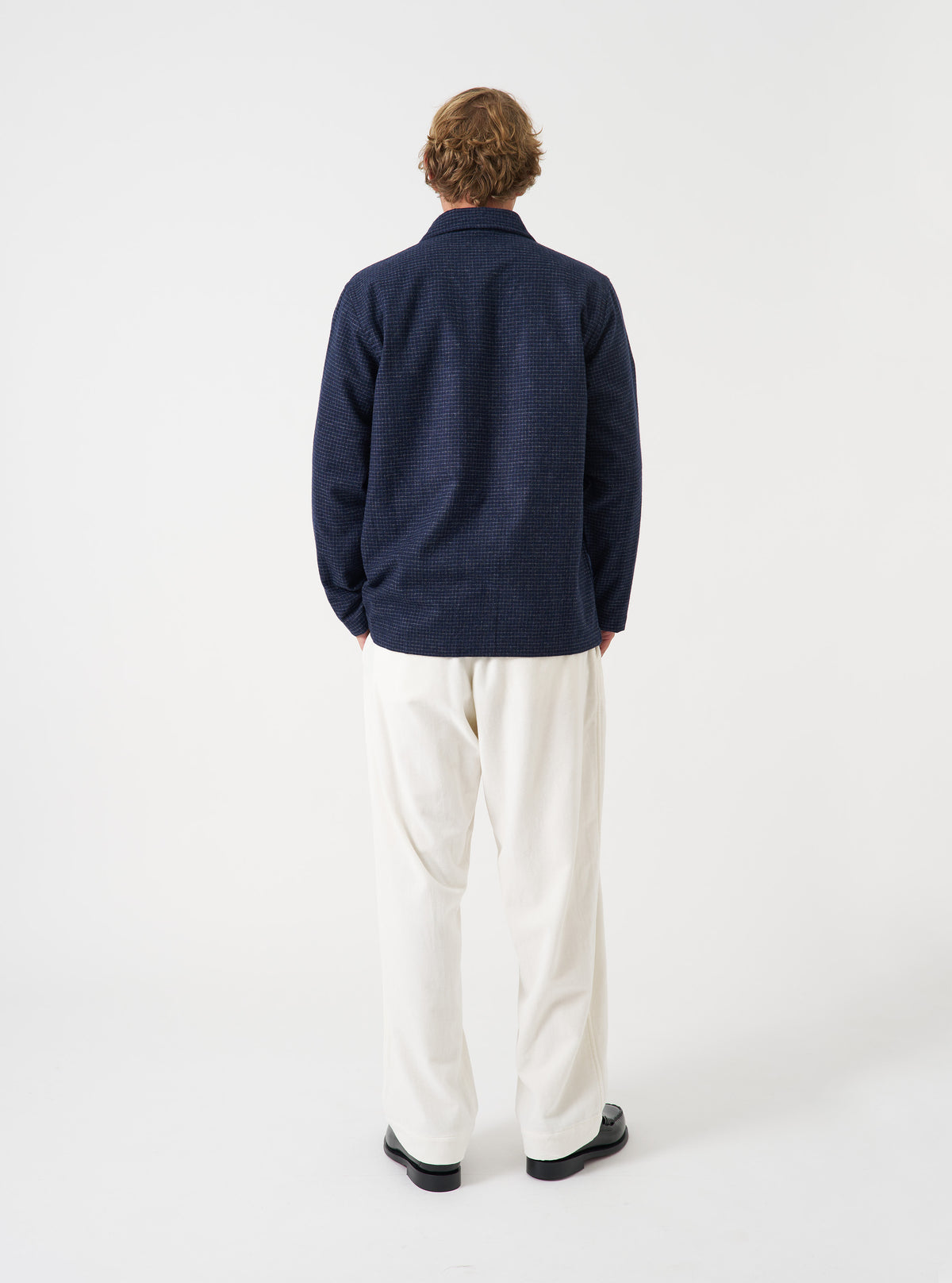 A model wearing the Navy Check Bobby Wool Mix Bakers Overshirt against a plain studio background. The overshirt features a subtle check pattern, a button-through front, four patch pockets, and a relaxed collar.